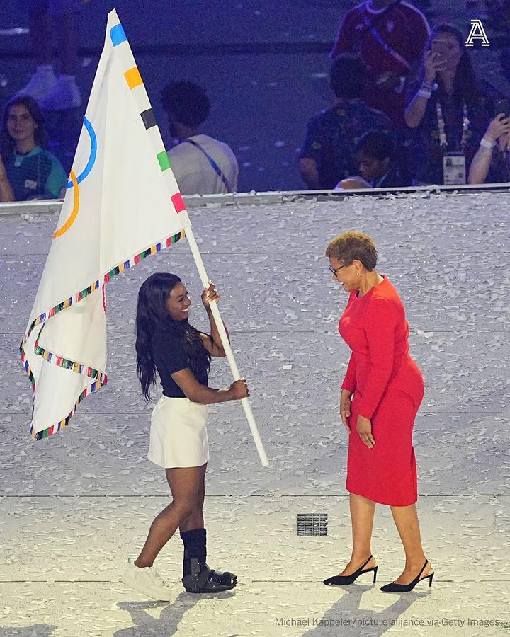 Why is Simone Biles in a walking boot? Biles held the Olympic flag with Los Angeles mayor Karen Bass during the handoff for the 2028 Olympics, but her left foot was the center of attention. She sustained an injury a few weeks prior to Paris, and here’s what we know... Full Details Below 