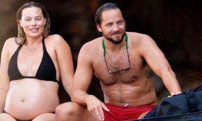 Pregnant Margot Robbie couldn’t take the smile off her face as she showcases her growing baby bump in a black bikini while relaxing with husband Tom Ackerley during sun-soaked break to Italy